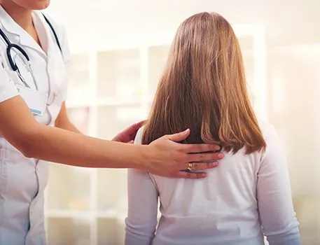 Doctor checking a patient's back during a wellness visit